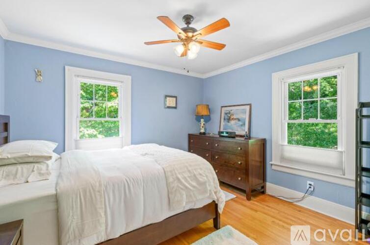 A bedroom with a bed, dresser, and a ceiling fan.