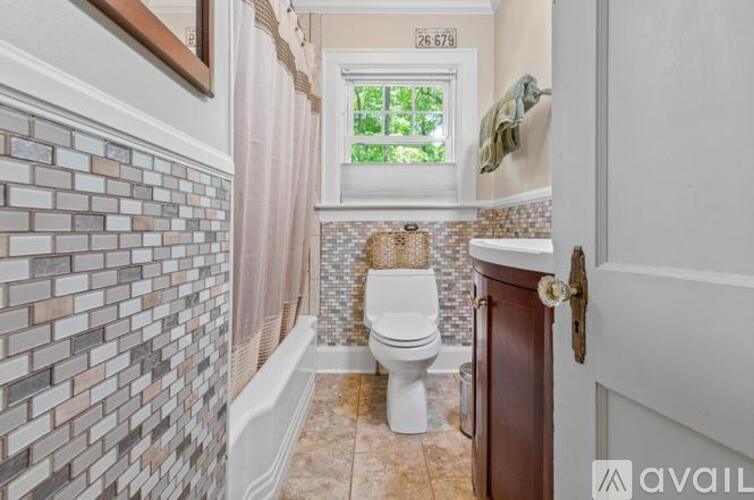 A bathroom with a toilet, a window, and a tiled wall.