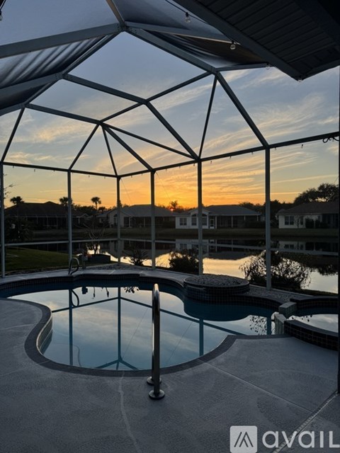 A pool enclosed by a metal frame with a sunset in the background.