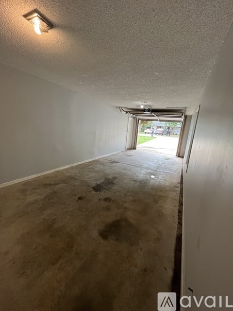 A room with a white wall and a door leading outside.