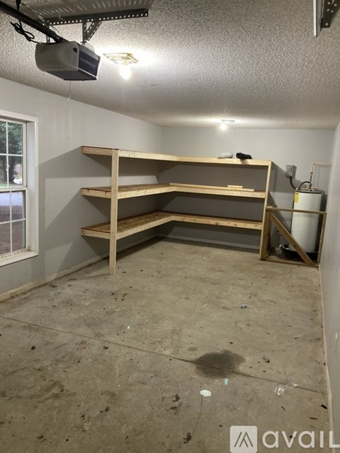 A room with a window and a wooden shelf.