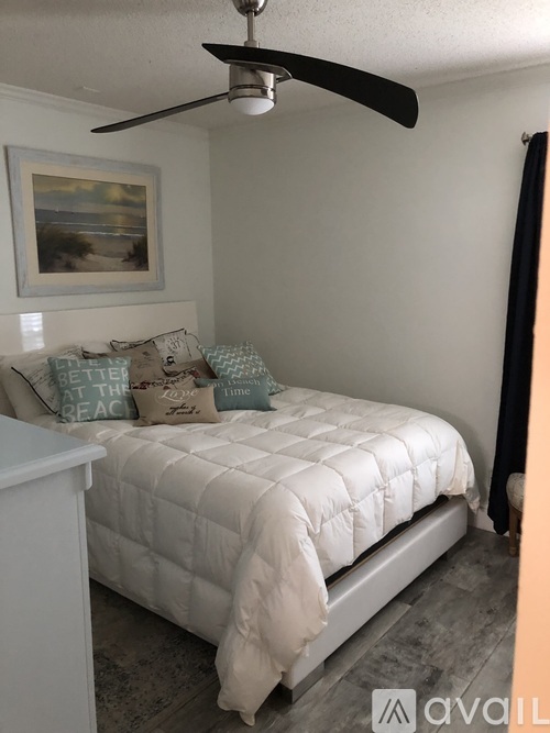 A bedroom with a white bed and a ceiling fan.