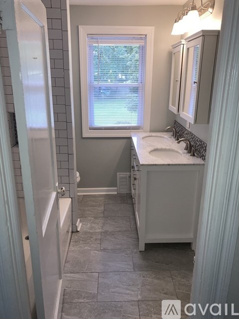 A bathroom with a white sink and grey tiles.