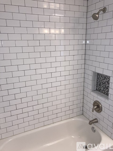 A white tiled shower with a glass door and a white bathtub.