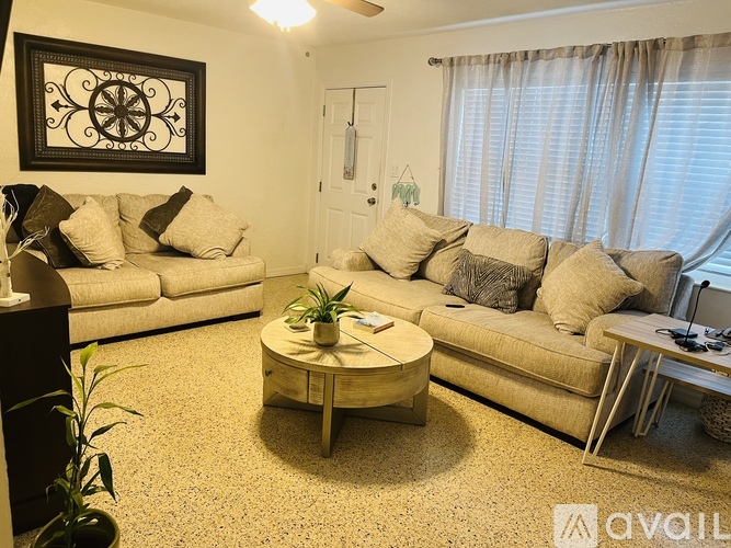 A living room with a white couch, a coffee table, and a painting on the wall.