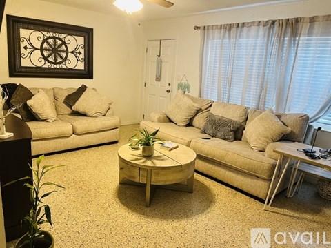 A living room with a white couch, a coffee table, and a painting on the wall.