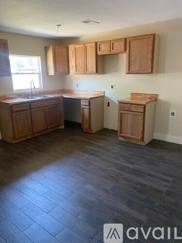 A kitchen with wooden cabinets and a grey floor.
