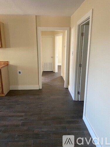 A hallway with a wooden floor and white walls.