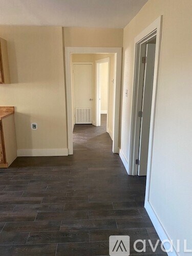 A hallway with a wooden floor and white walls.