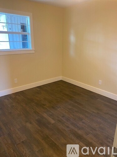 A room with wooden flooring and a window.