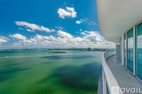 A modern building with a curved white roof overlooks a body of water.