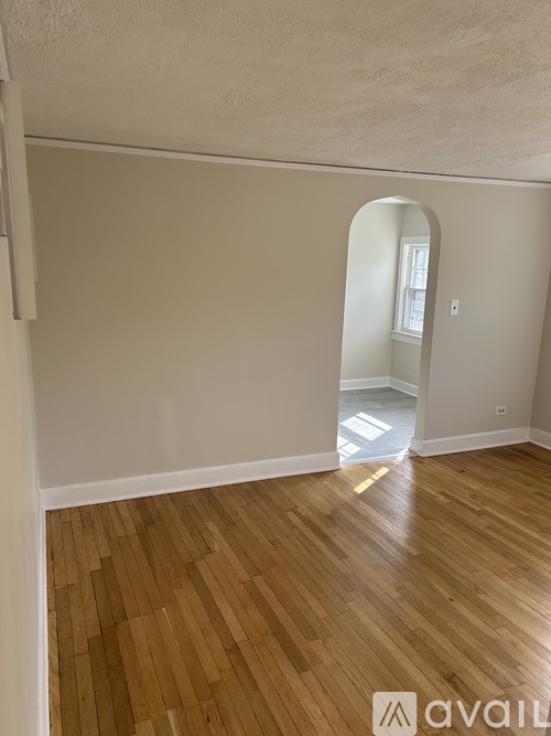 A room with wooden flooring and a white wall with a mirror.