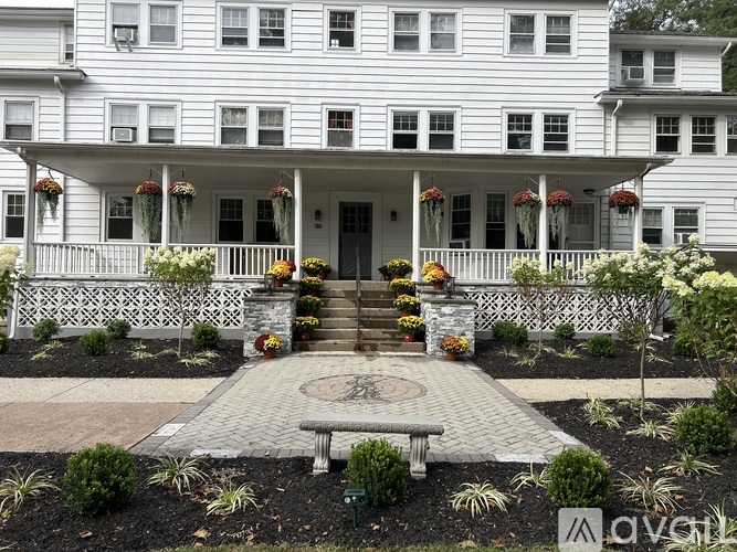 A white house with a front porch and a circular walkway in front.