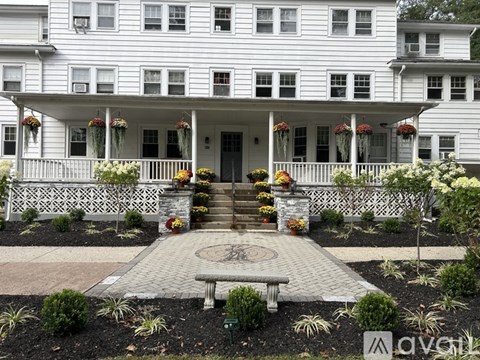 A white house with a front porch and a circular walkway in front.
