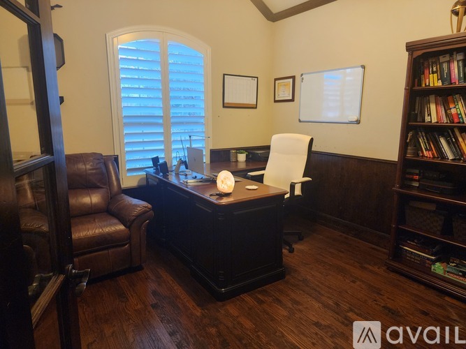 A room with a brown leather chair and a wooden desk.