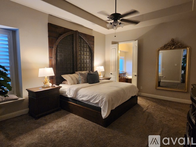 A bedroom with a large bed, a ceiling fan, and a large mirror.