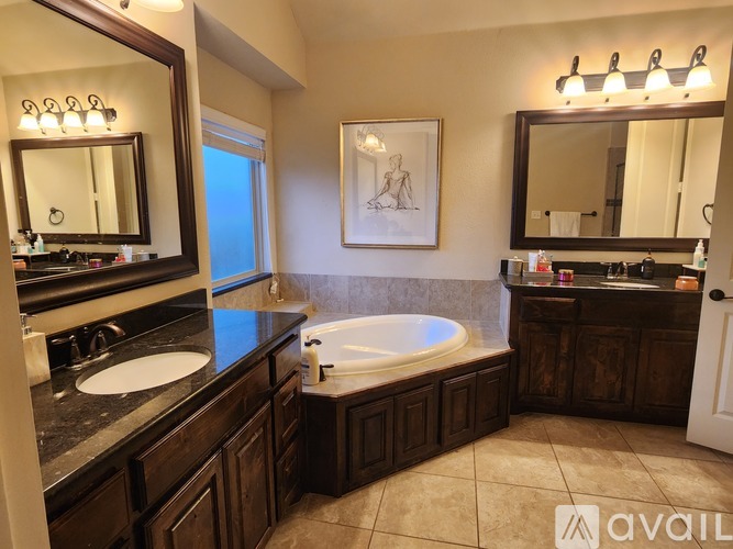 A bathroom with a large tub and double sinks.