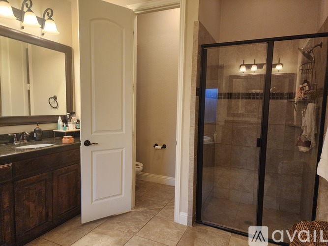 A bathroom with a white door and a mirror above a sink.