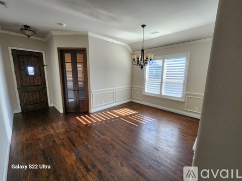 A room with wood flooring and a chandelier.