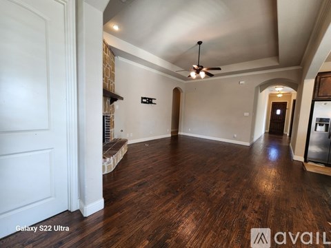 A spacious room with wood flooring and a ceiling fan.