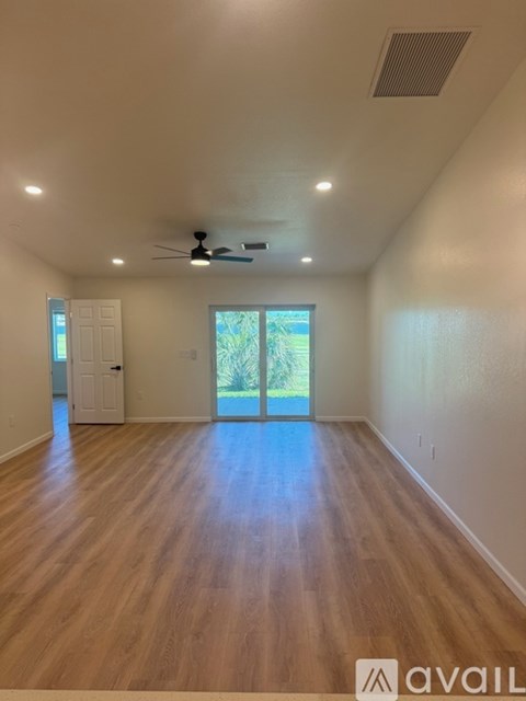 A spacious room with wooden floors and a ceiling fan.