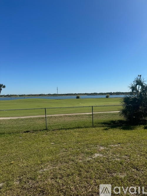 A grassy field with a fence and a distant view of a body of water.