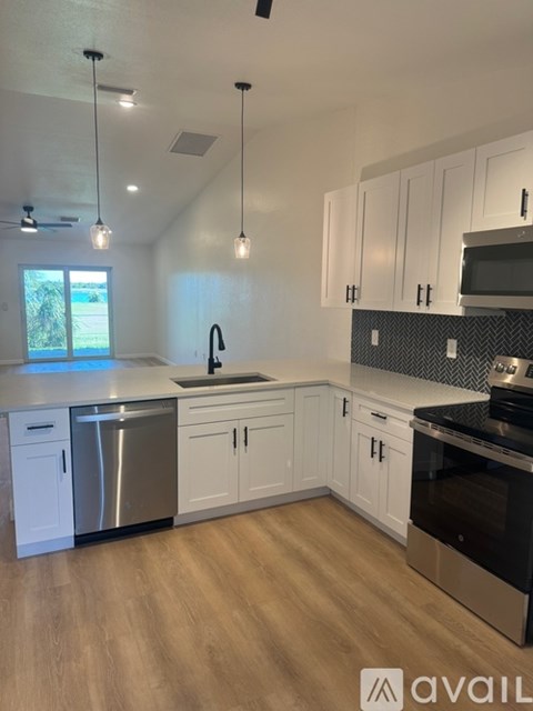 A kitchen with white cabinets and a wooden floor.