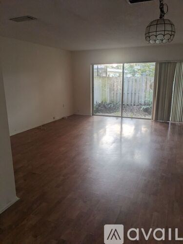 A room with wooden flooring and a sliding glass door leading to a backyard.