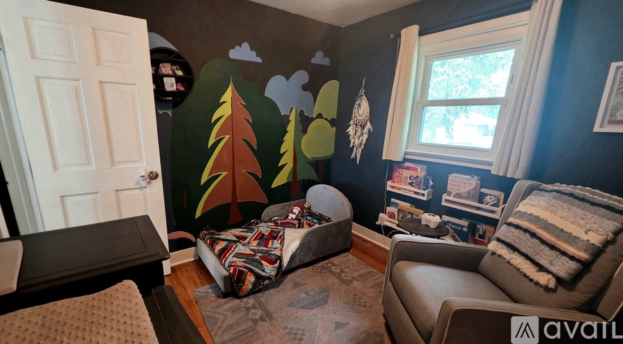 A room with a mural of trees and a white door.