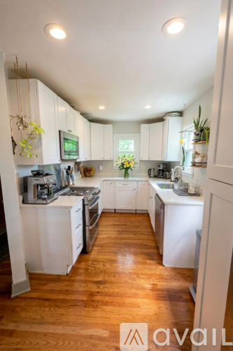 A kitchen with white cabinets and wooden floors.