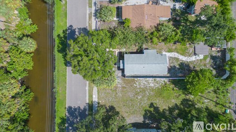 A bird's eye view of a house surrounded by trees and a road.