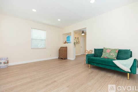A living room with a green couch and wooden floors.