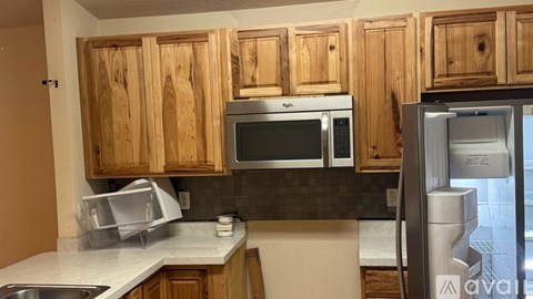 A kitchen with wooden cabinets and a stainless steel refrigerator.