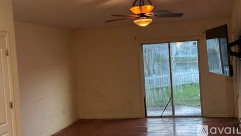 A room with a ceiling fan and sliding glass doors.