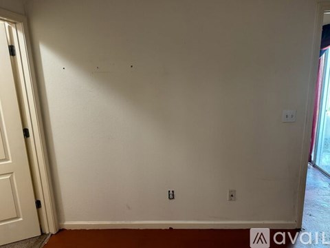 A room with white walls and a door on the left.