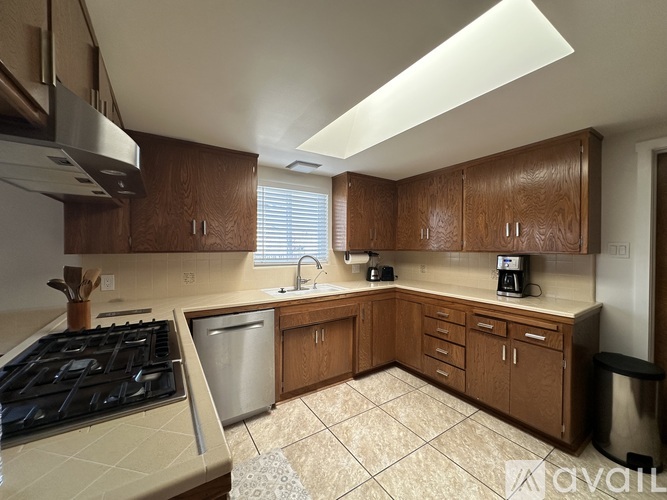 A kitchen with wooden cabinets and a stainless steel dishwasher.
