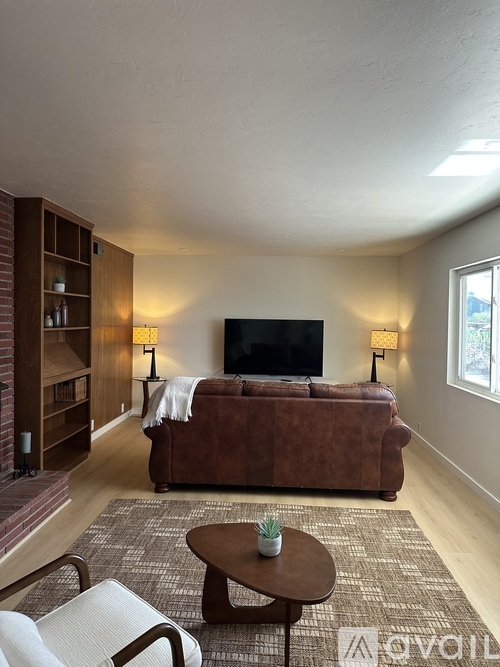 A living room with a brown couch, a coffee table, and a television.
