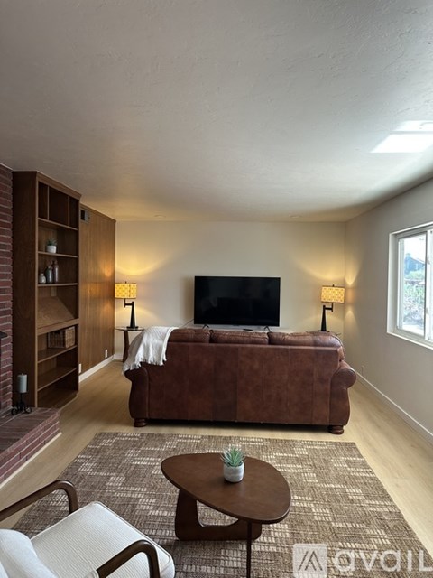 A living room with a brown couch, a coffee table, and a television.