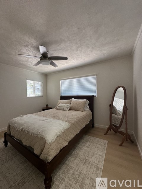 A bedroom with a bed, a fan, and a mirror.