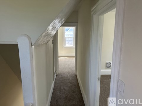 A long hallway with a carpeted floor and white walls.