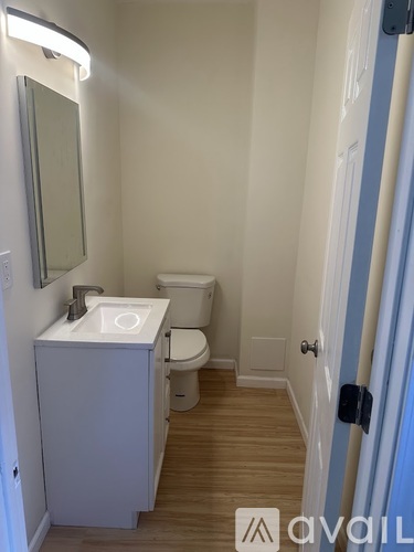 A bathroom with a toilet, sink, and mirror.
