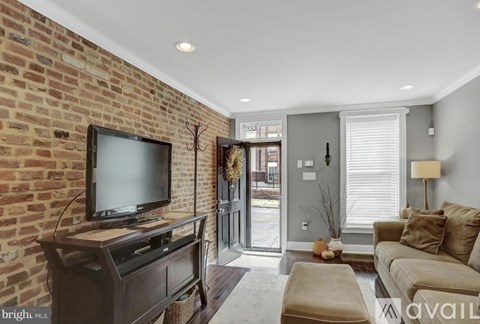 A living room with a brick wall and a television on a stand.