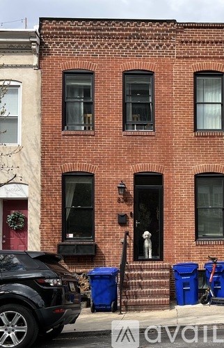 A dog is standing in the doorway of a red brick building.