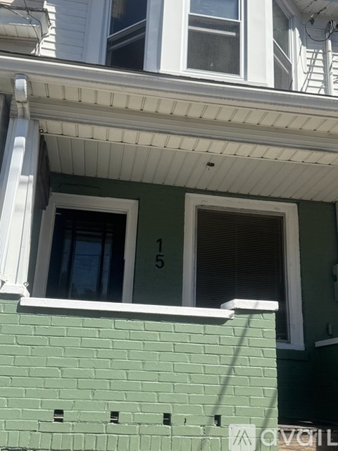 A green building with a white trim and a window with the number 15 on it.
