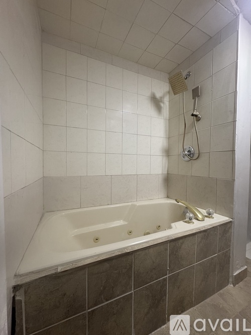A bathroom with a white tub and a shower head.