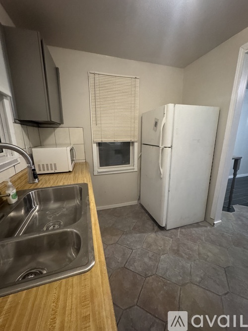 A kitchen with a white fridge, sink, and wooden countertop.