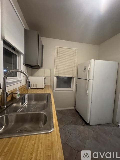 A kitchen with a white fridge, a sink and a window.