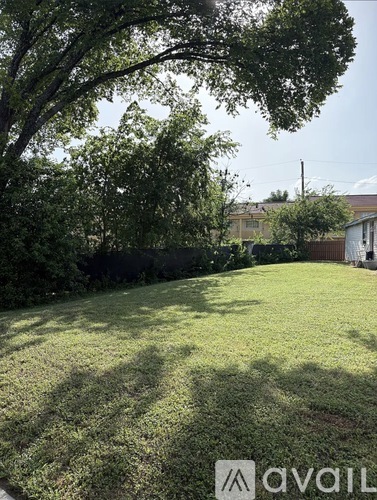 A backyard with a well-maintained lawn and trees.