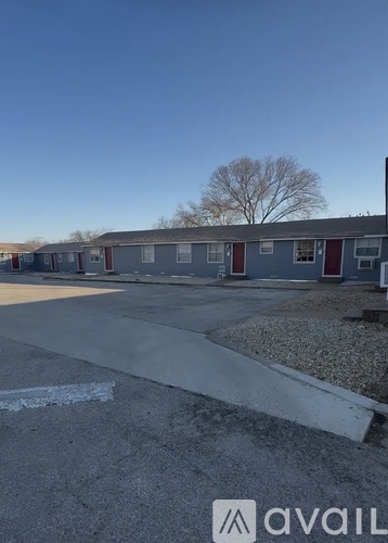 A parking lot with a building in the background and a tree with no leaves.