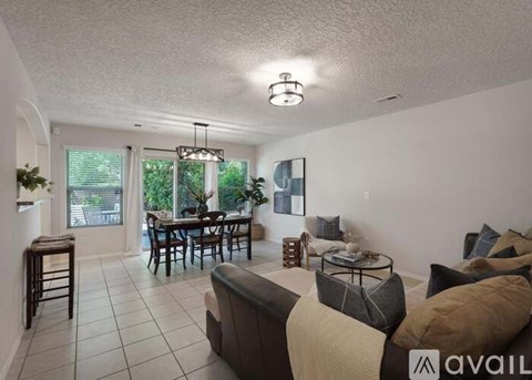 A living room with a dining table and chairs, a couch, and a chandelier.